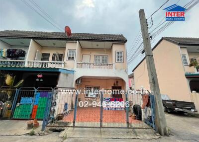 Exterior view of a townhouse with a gated entrance and driveway