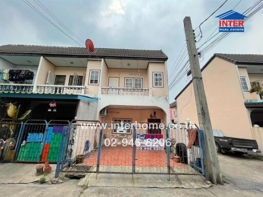 Exterior view of a townhouse with a gated entrance and driveway