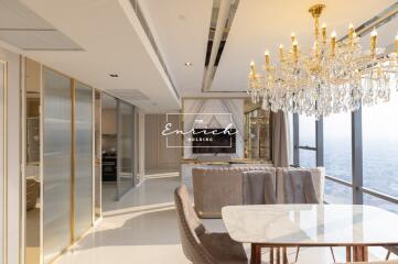 Modern living and dining area with a large chandelier and city view