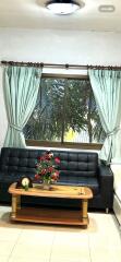 Living room with black sofa, coffee table, and large window with curtains