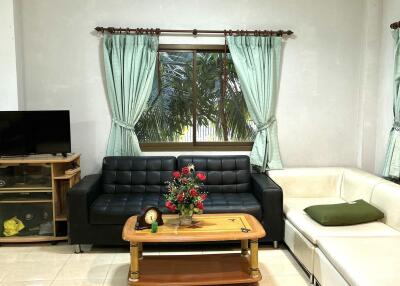 Bright living room with black and white couches, a coffee table, and a TV stand