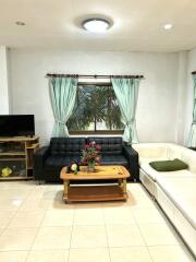 Bright living room with black and white couches, a coffee table, and a TV stand