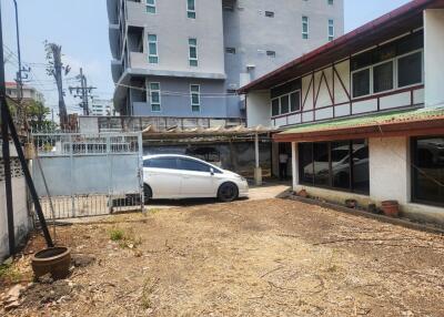 A yard area with a parked car and adjacent buildings