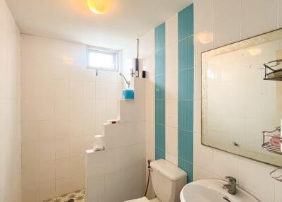 Bathroom with white and blue tiles, pedestal sink, toilet, and a shower area