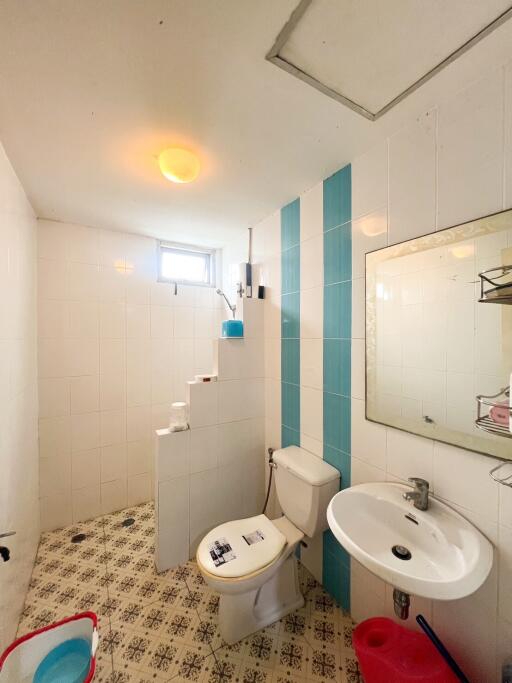 Bathroom with white and blue tiles, pedestal sink, toilet, and a shower area