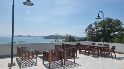 Outdoor terrace with a view of the sea, featuring wooden seating and dining arrangements