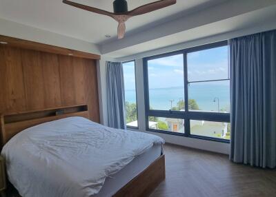 Bedroom with large window offering ocean view and wooden accent wall