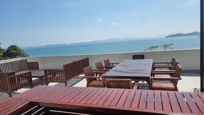 Outdoor dining area with wooden furniture overlooking a scenic ocean view