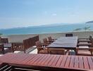 Outdoor dining area with wooden furniture overlooking a scenic ocean view