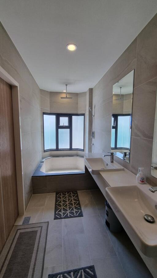 Modern bathroom with double sinks, bathtub, and large window