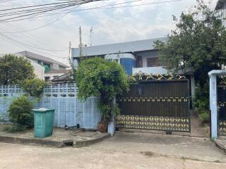 Front view of the property with fenced entrance and surrounding greenery