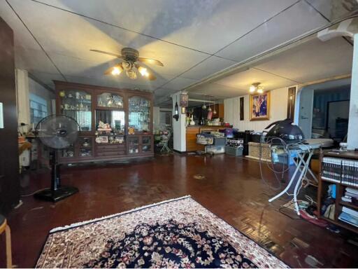 Main living area with hardwood floors, ceiling fan, and various furnishings