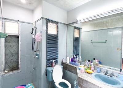 Bathroom with blue sink and toilet, large mirror, and various toiletries.