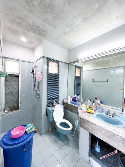 Bathroom with blue sink and toilet, large mirror, and various toiletries.