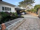 Exterior view of a house with a pond and driveway leading to a carport