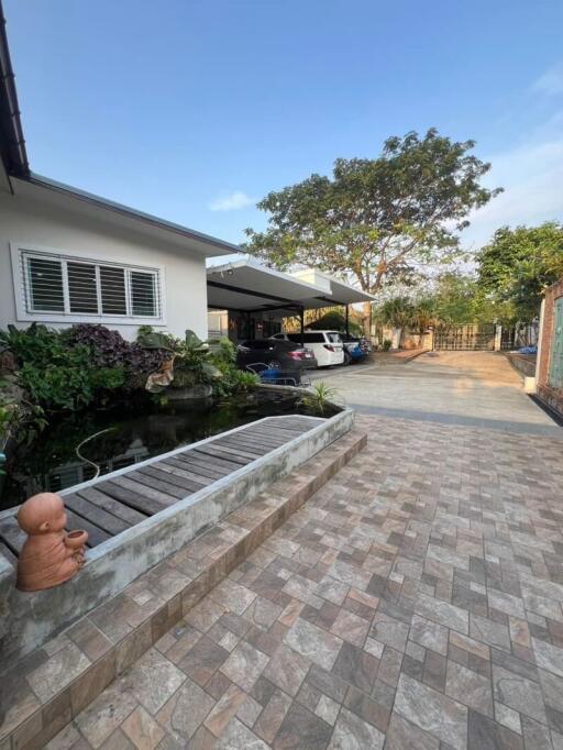 Exterior view of a house with a pond and driveway leading to a carport