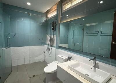 Spacious modern bathroom with glass shower doors, sink, and toilet