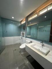 Spacious modern bathroom with glass shower doors, sink, and toilet