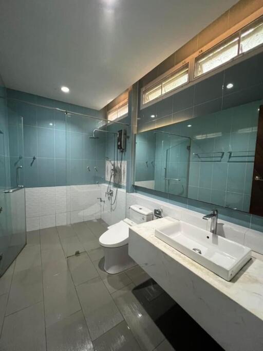 Spacious modern bathroom with glass shower doors, sink, and toilet