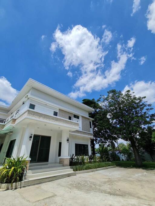 Modern two-story house with a clear blue sky and lush trees