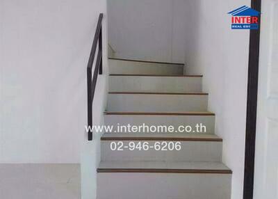Staircase with white walls and dark handrail