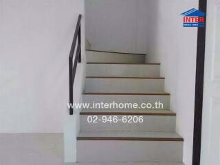 Staircase with white walls and dark handrail