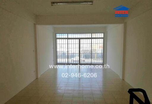 Empty living room with large windows and tiled floor