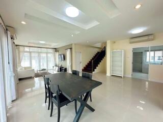 Modern living room with dining area, stairway, and large windows