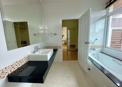 Modern bathroom with large mirror, sink, and bathtub