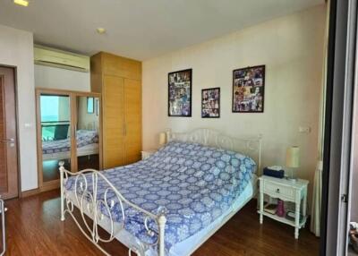 Spacious bedroom with wooden flooring, a double bed, wall art, and side tables