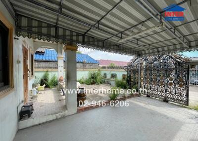 A spacious covered patio area with seating and ornamental gate