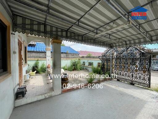 A spacious covered patio area with seating and ornamental gate