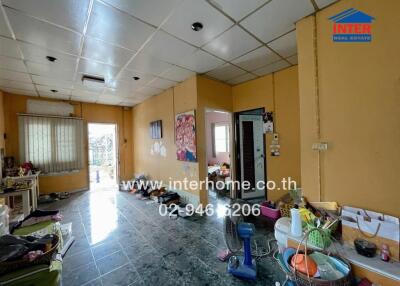 Living room with tiled flooring, yellow walls, and various household items.