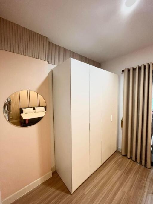 Bedroom with white wardrobe and round wall mirror