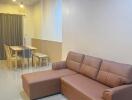 Modern living room with a brown sectional sofa and a dining area.