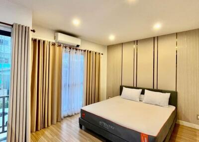 Spacious bedroom with a large bed, wooden flooring, and ample lighting