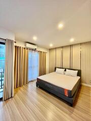 Spacious bedroom with a large bed, wooden flooring, and ample lighting