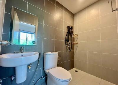Modern bathroom with tiled walls, sink, toilet, and shower area