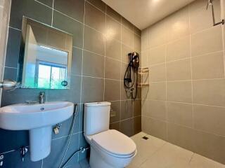 Modern bathroom with tiled walls, sink, toilet, and shower area