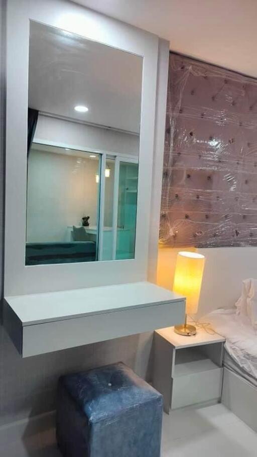 Modern bedroom with vanity mirror, bedside table, lamp, and cushioned stool