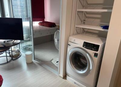 Small living area with washing machine and view into bedroom