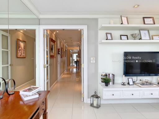 Well-lit living room with hallway, built-in shelves and TV