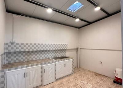 Spacious kitchen area with modern lighting and checkered backsplash