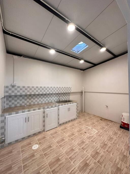 Spacious kitchen area with modern lighting and checkered backsplash