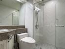 Modern bathroom with glass shower, toilet, and vanity