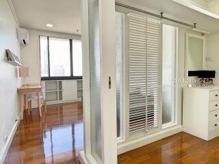 Spacious bedroom with hardwood floors and large window