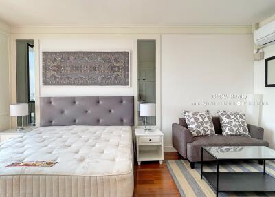 Modern bedroom with a bed, sofa, lamps, and wall art