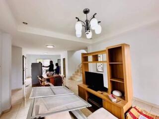 Modern living room with wooden furniture, TV, and staircase