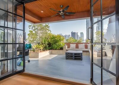 Spacious outdoor patio with a city view, wooden ceiling with fan, and seating area