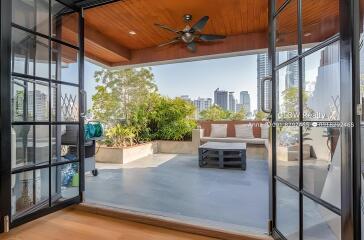 Spacious outdoor patio with a city view, wooden ceiling with fan, and seating area